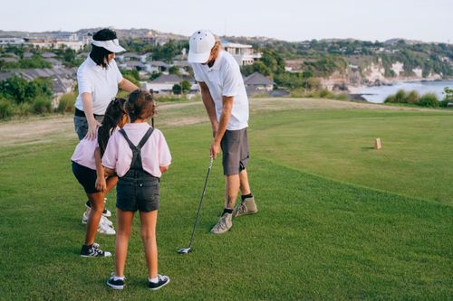 Free A family enjoying a golf lesson together on a sunny day at a beautiful coastal golf course. Stock Photo