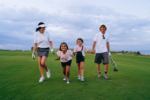 Free A happy family walking together on a lush golf course, enjoying a sunny day. Stock Photo