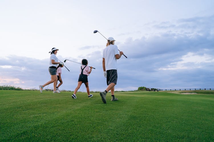 Family Carrying Golf Clubs While Walking 