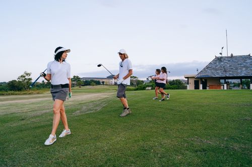 Free A family enjoys playing golf together, showing teamwork and leisure on a bright day. Stock Photo