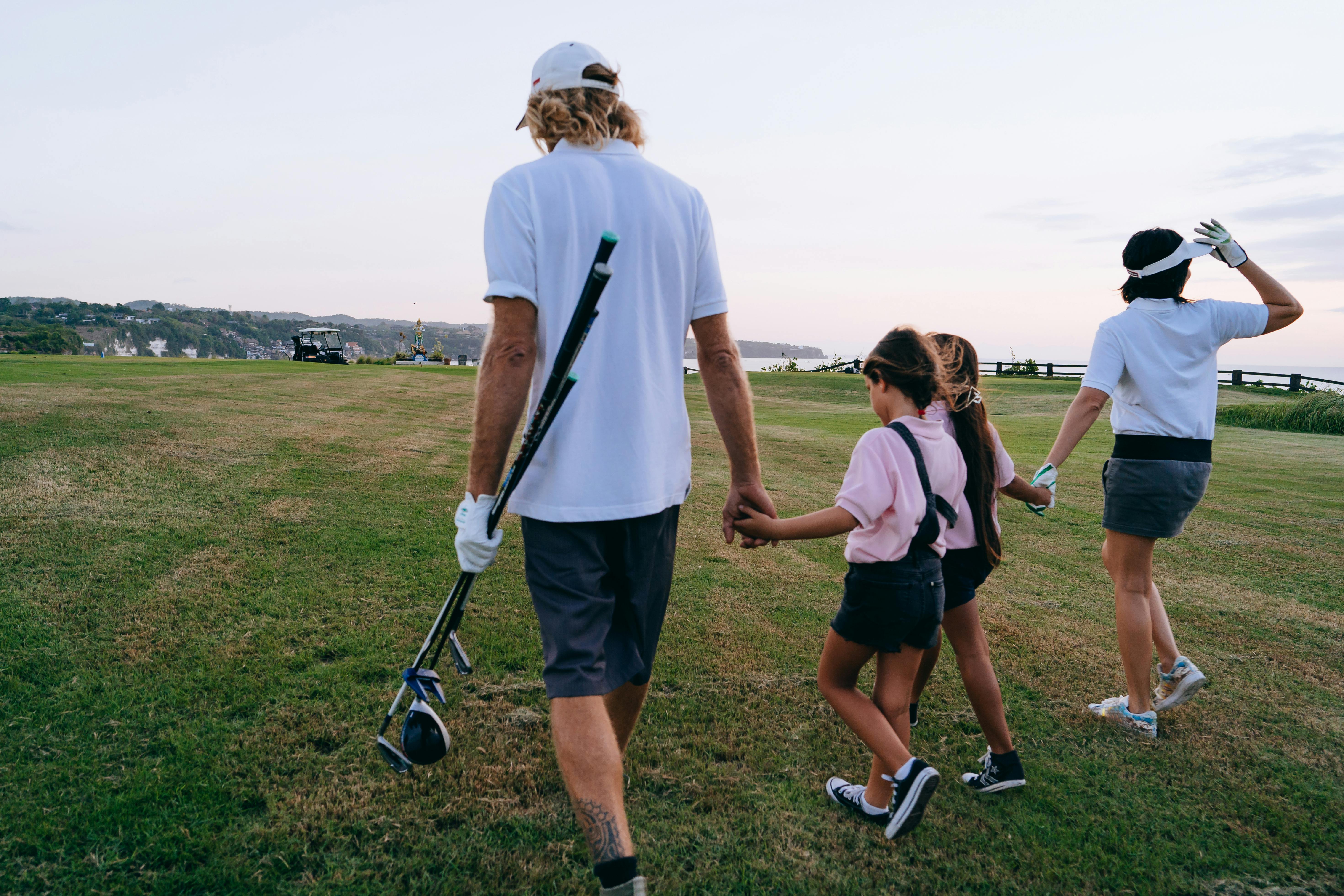 man in white polo shirt and shorts holding golf clubs