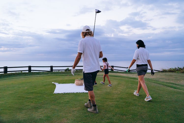 A Family Walking Towards A Picnic Blanket On A Golf Course