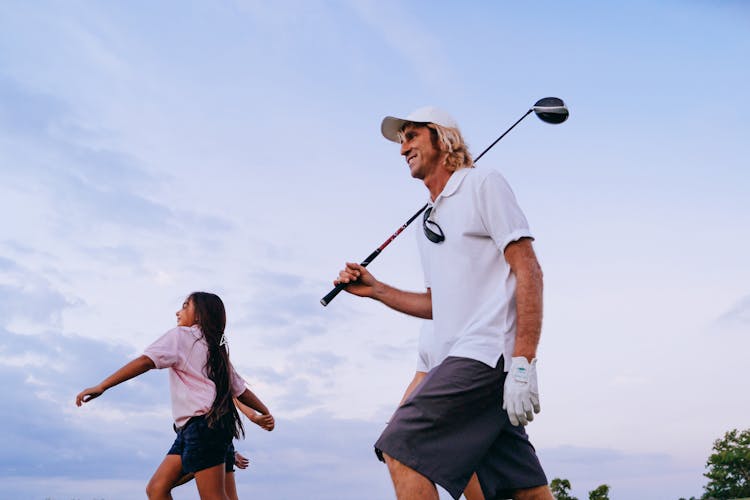 A Man Holding A Golf Club While Walking