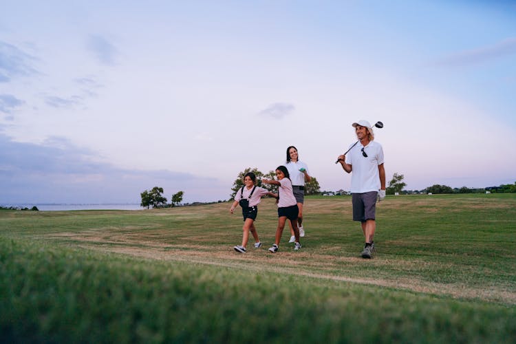 Family Carrying Golf Clubs While Walking