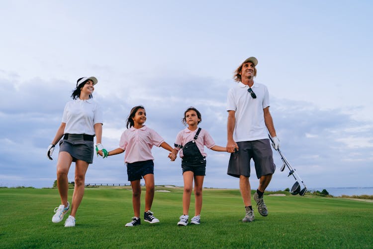 Family Carrying Golf Clubs While Walking