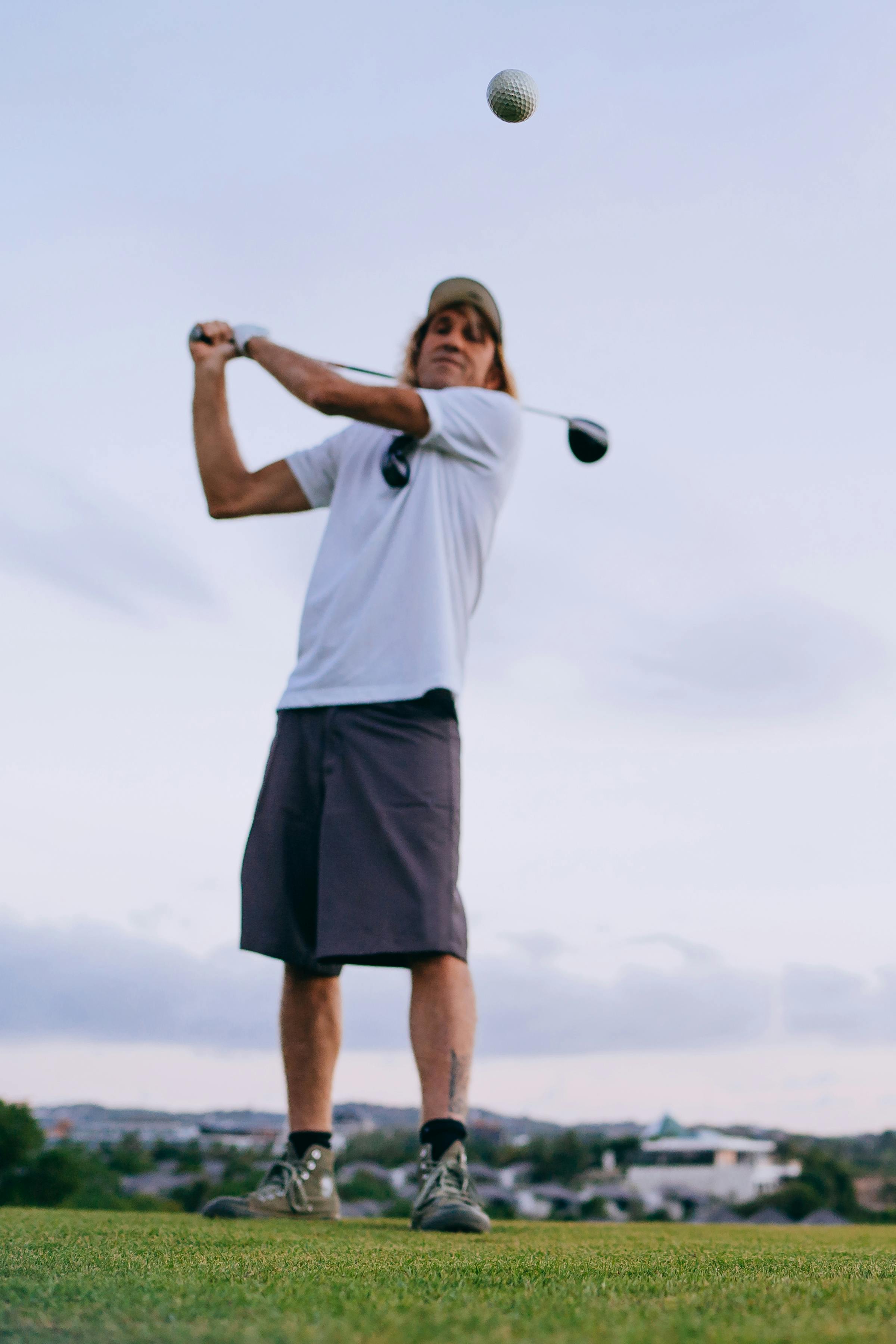 man in white t shirt playing golf in tilt shift lens