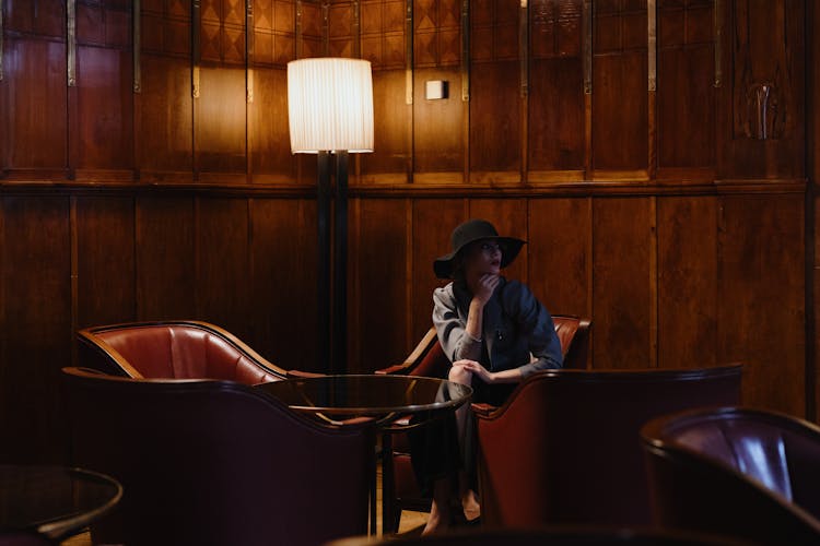 A Woman With A Black Hat Sitting On A Chair