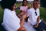 Woman in White Polo Shirt Sitting on Green Grass Field