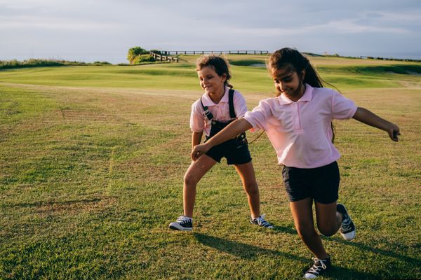 Two girls running and playing on green grass