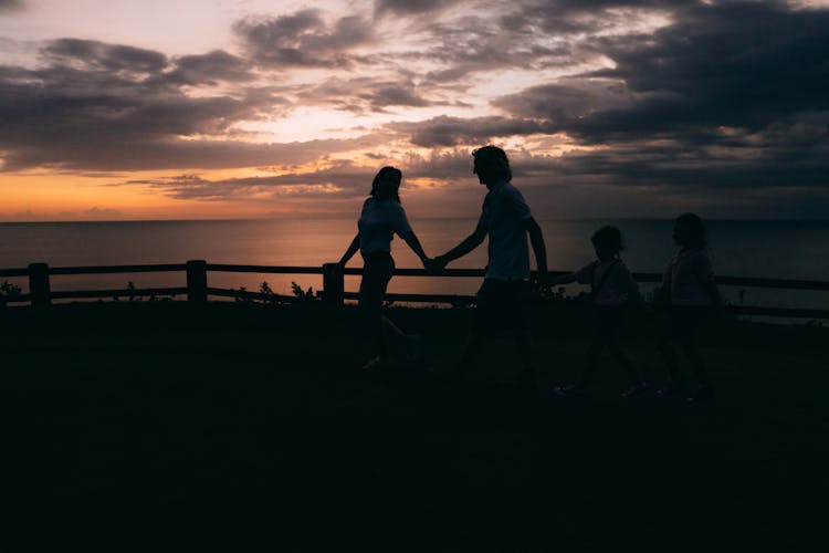 A Silhouette Of A Family Walking While Holding Hands