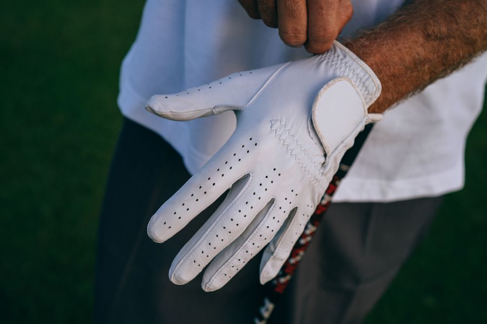 A tournament gift set on a table: leather headcover, valuables pouch and a small engraved decanter, each with a small tone-on-tone club mark.