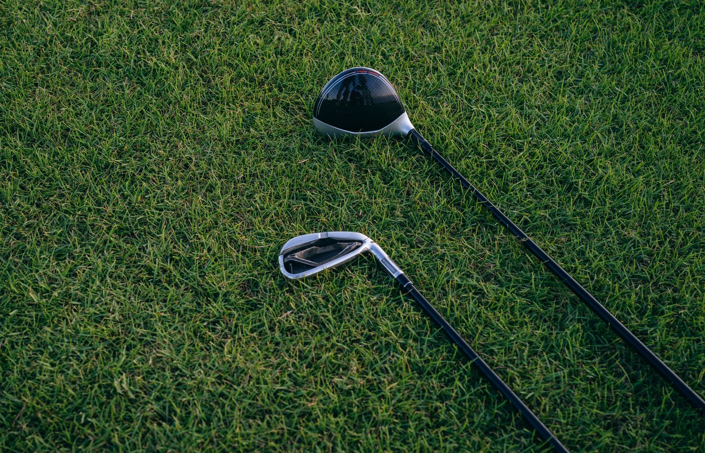 A close-up view of two golf clubs resting on neatly manicured grass, perfect for golf enthusiasts.