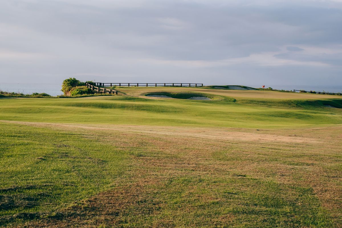 Wide view of a green golf course landscape under an overcast sky
