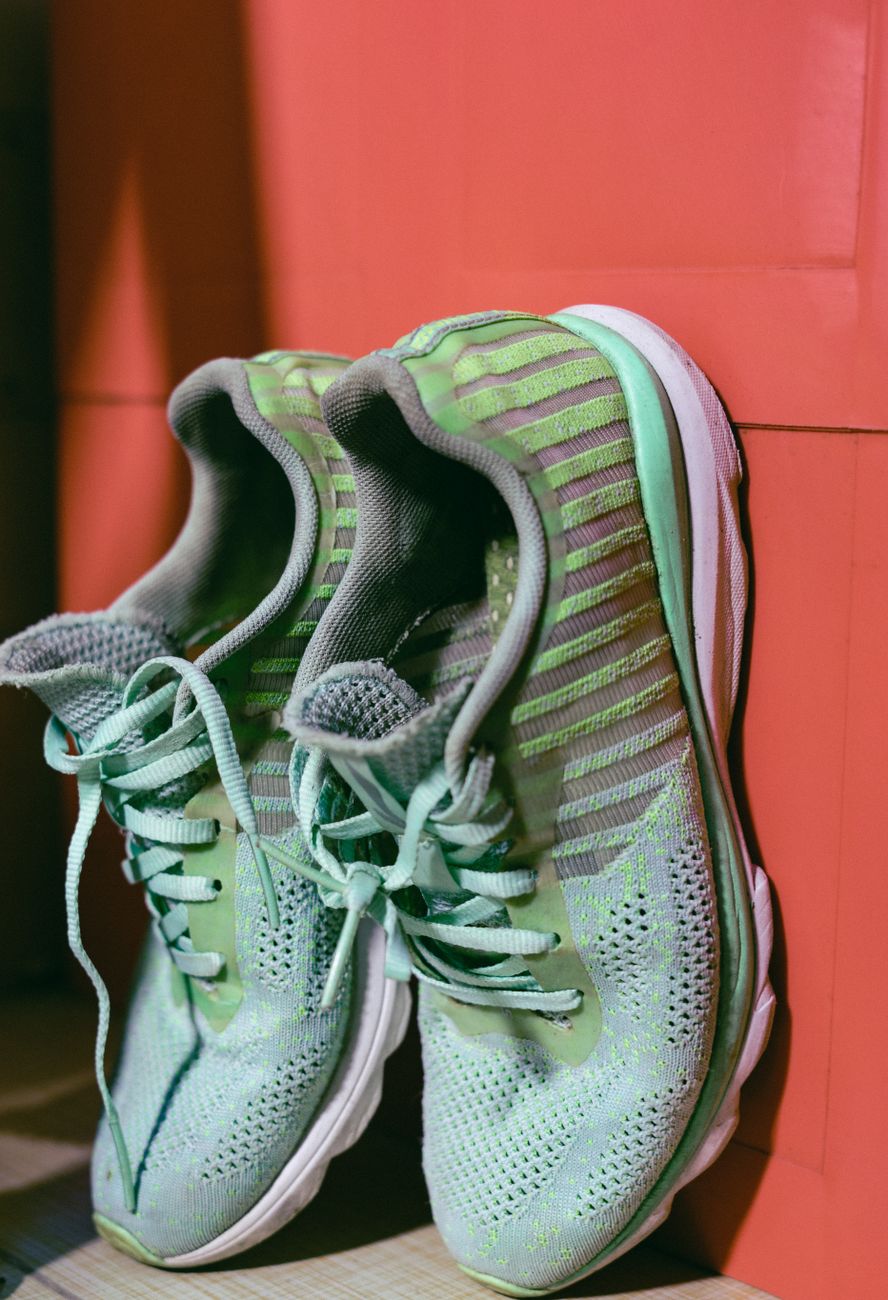 Close-up of vibrant green sneakers leaning against a bold red backdrop
