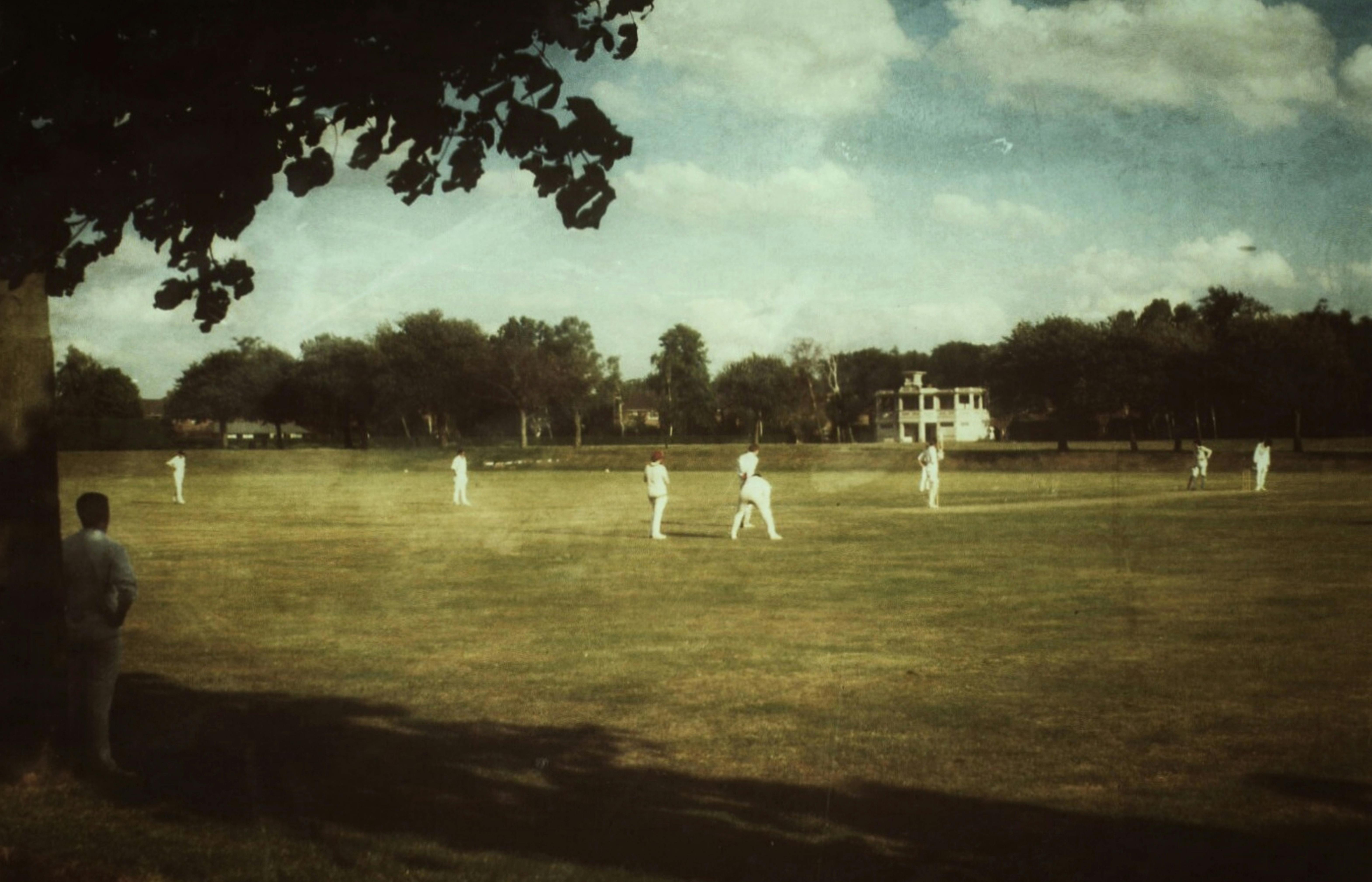 people in white clothes playing cricket on field