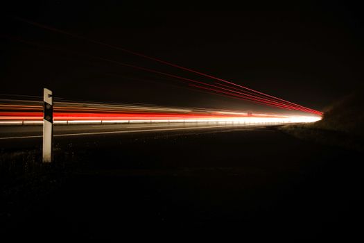 Captivating long-exposure image of traffic lights creating dynamic streaks at night on a deserted road.