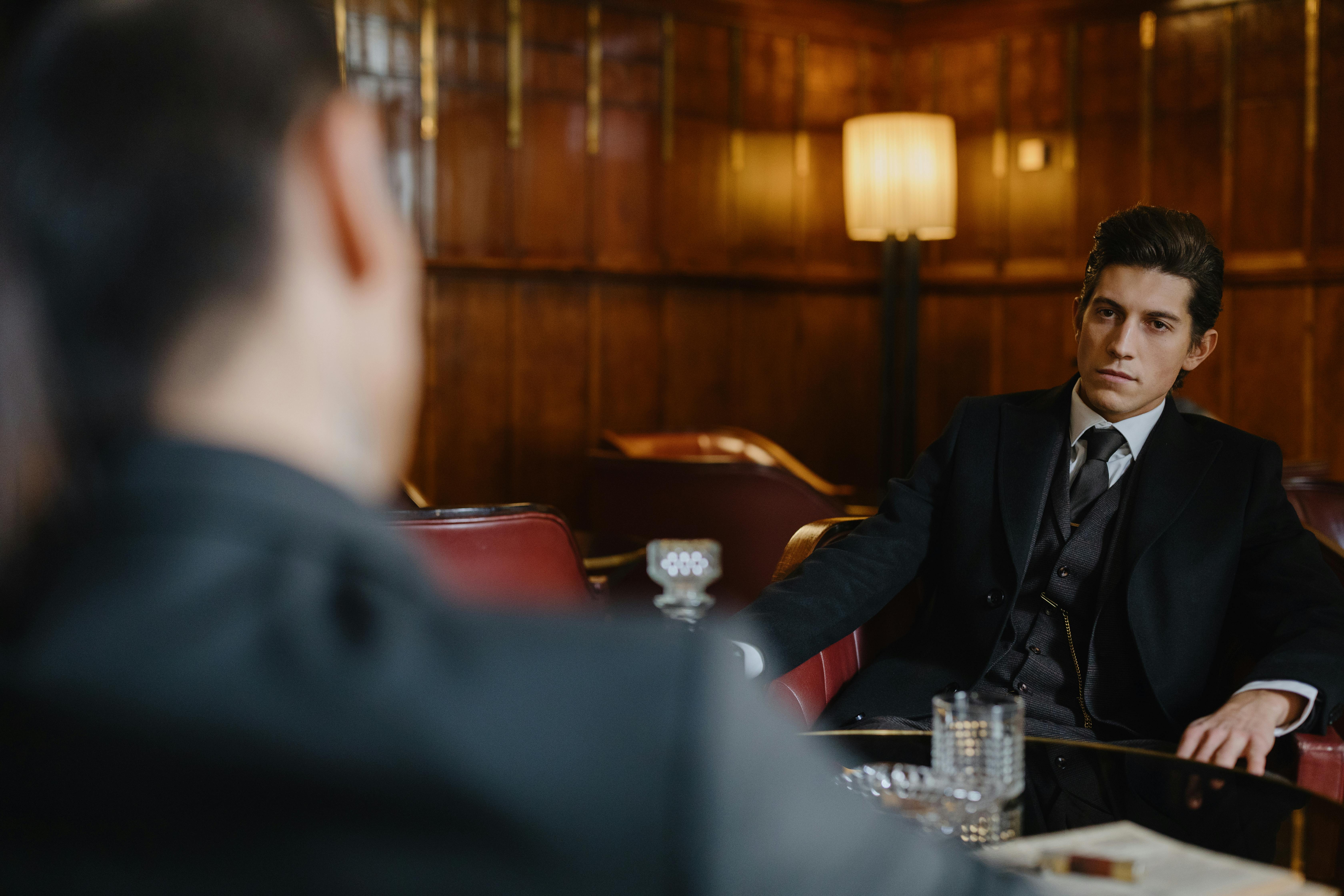 man in black suit sitting on an armchair