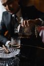 A Man in a Suit Pouring Whiskey from a Decanter