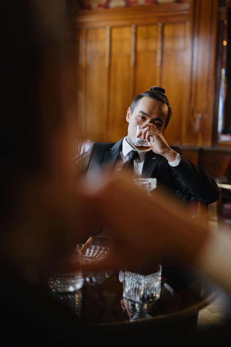 A Man In A Suit Drinking Whiskey