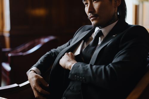 Free A confident man in formal attire seated indoors, reflecting professionalism and style. Stock Photo