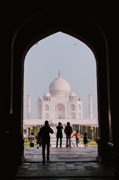 Capture of the Taj Mahal framed by an arched entrance with visitors in the foreground.