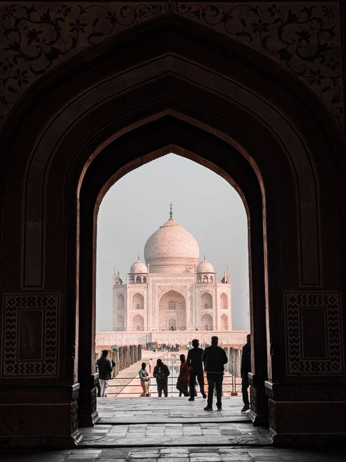 Free Silhouette of people in front of the Taj Mahal viewed through an ornate archway. Stock Photo