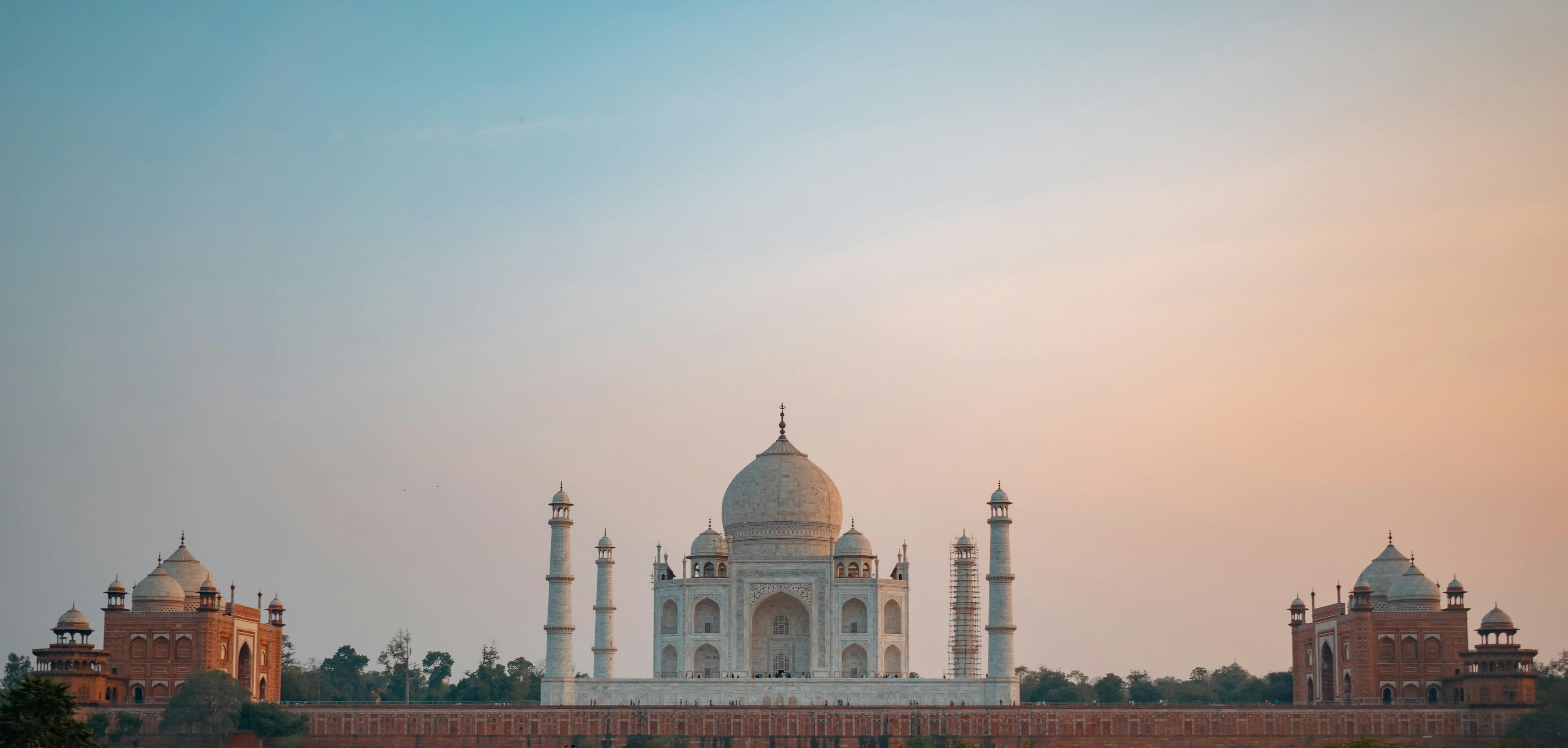 Panoramic view of the Taj Mahal at sunset showcasing the iconic mausoleum under a clear sky.