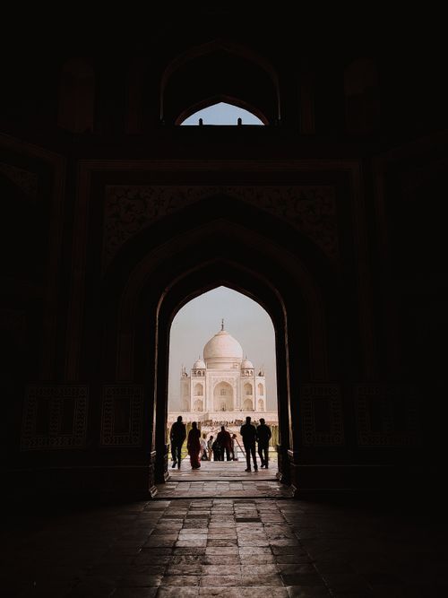 Free A striking silhouette of people entering the iconic Taj Mahal through a grand arched entrance. Stock Photo