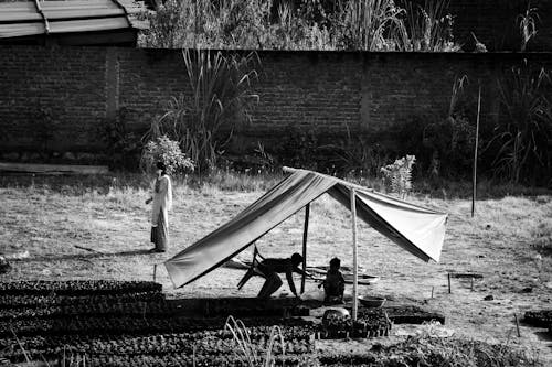 Grayscale Photo of People Under a Tent