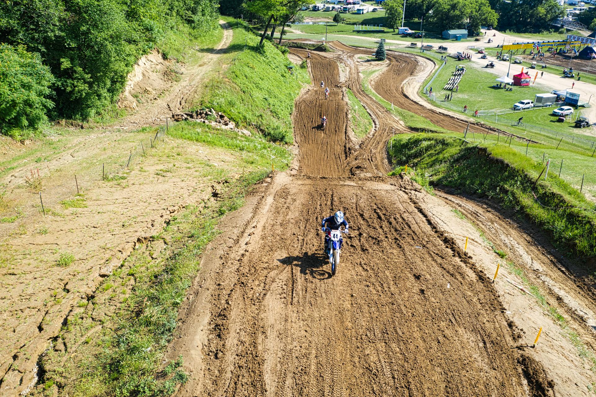 A thrilling aerial view of a motocross race on a dirt track surrounded by greenery in Millville, MN.