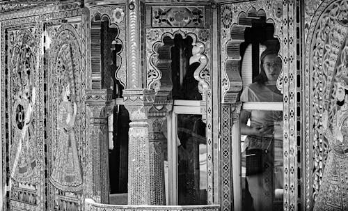 Grayscale Photo of Woman Standing in Front of Door