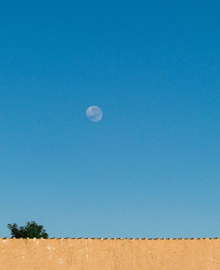 A Waning Crescent Moon On A Clear Blue Sky