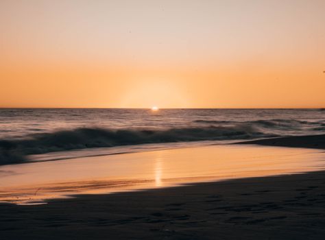 A tranquil beach scene at sunset with gentle waves and golden light, captured along the Australian coastline.