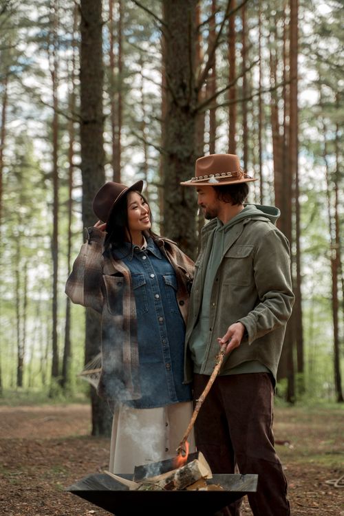 Free A couple enjoying a peaceful camping moment with a campfire in the forest. Stock Photo