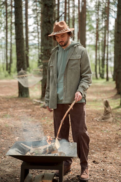 A Man Holding a Stick while Standing by a Fire Pit