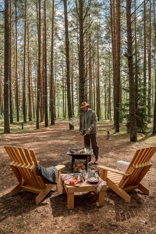 A Man Making a Campfire Near Trees