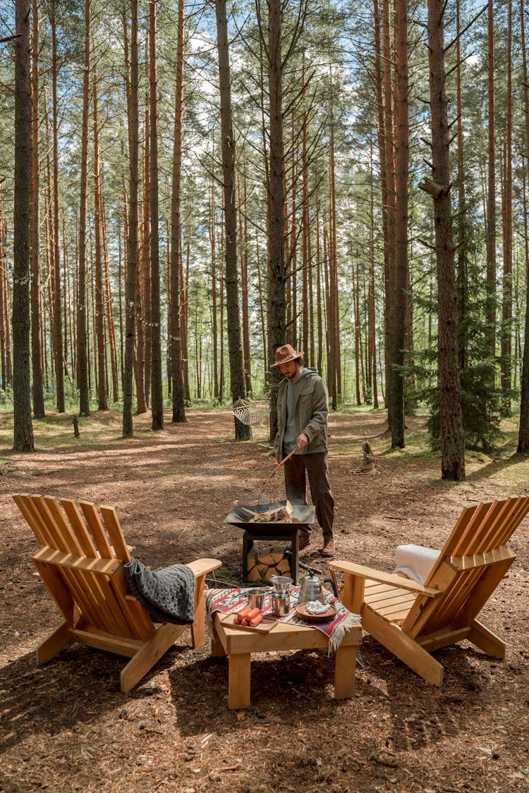 A Man Making A Campfire Near Trees