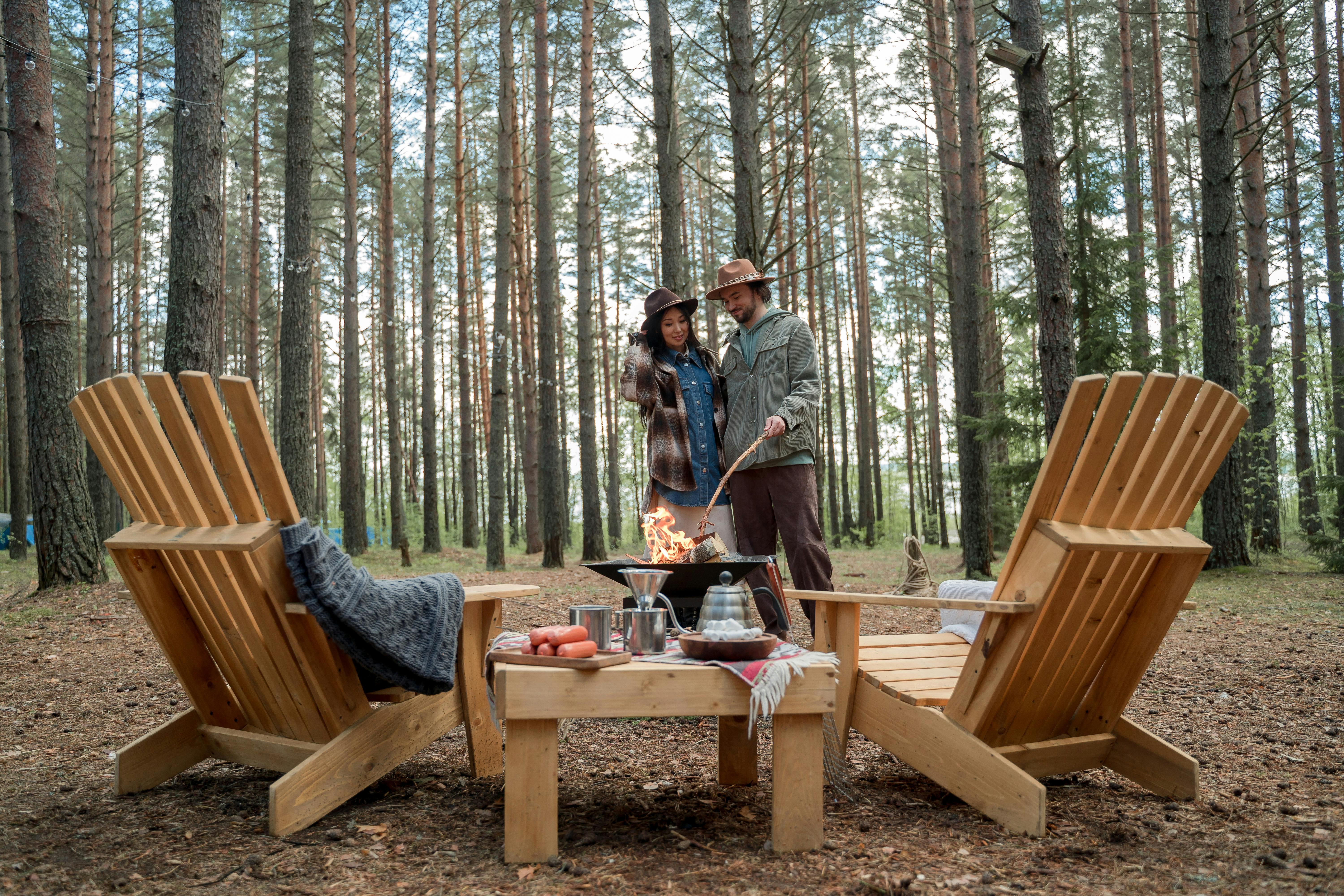 a couple standing near a fire pit in the woods