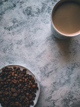 Overhead view of a coffee cup and beans on a textured table, creating a rustic ambiance.