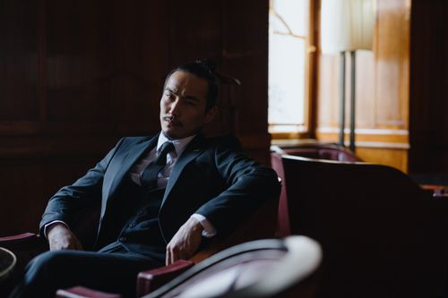 Free Man in formal business attire sitting in a stylish, dimly lit room. Stock Photo