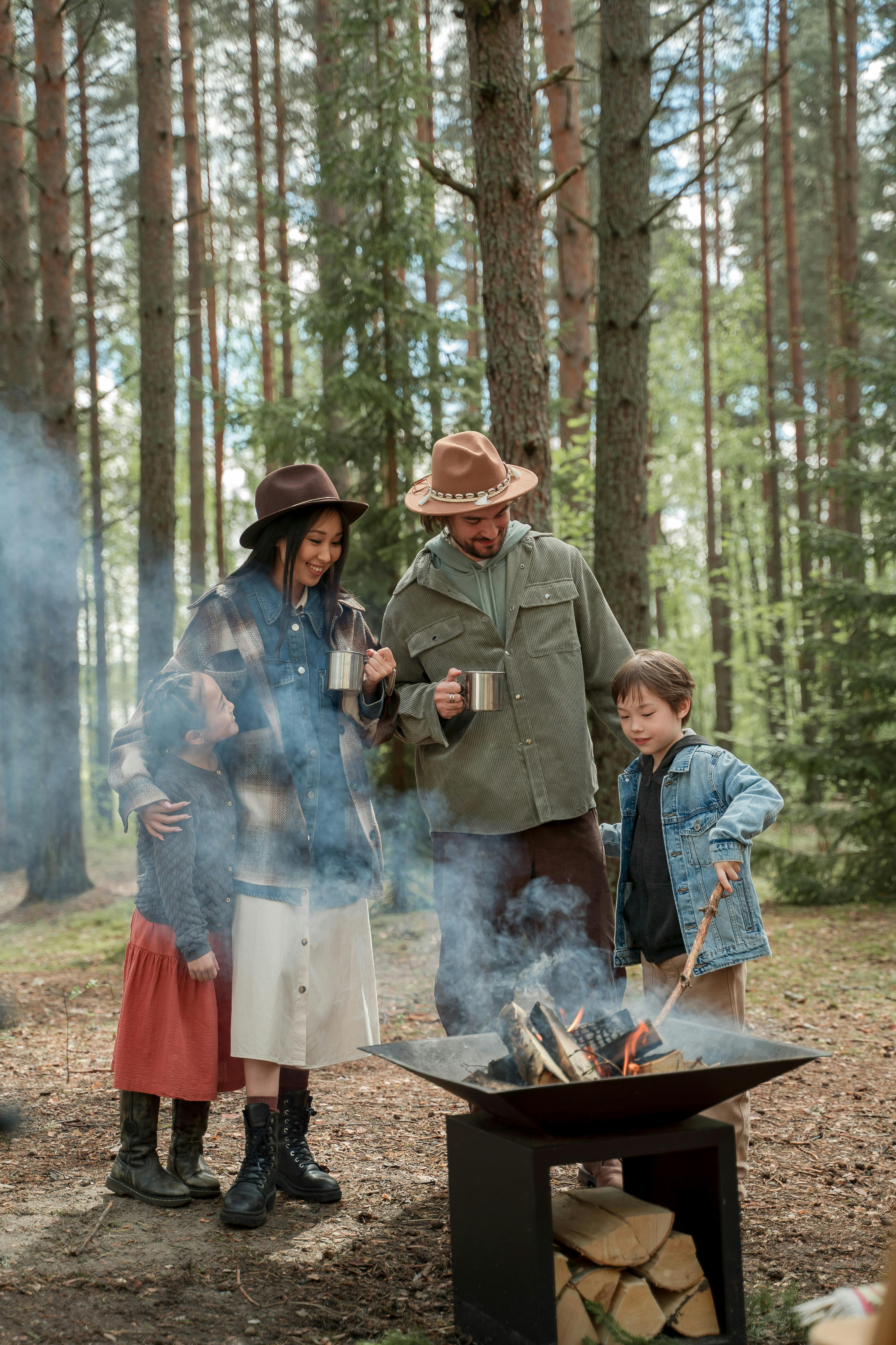 a happy family standing by a firepit in the woods