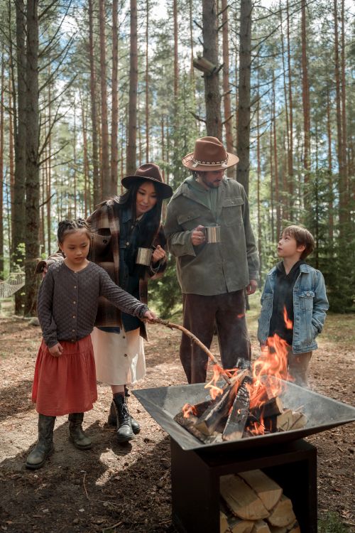 Free A family bonding around a campfire in a serene forest setting. Stock Photo