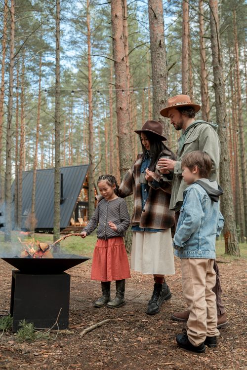 Free Family with kids enjoying a campfire in the woods, surrounded by nature. Stock Photo