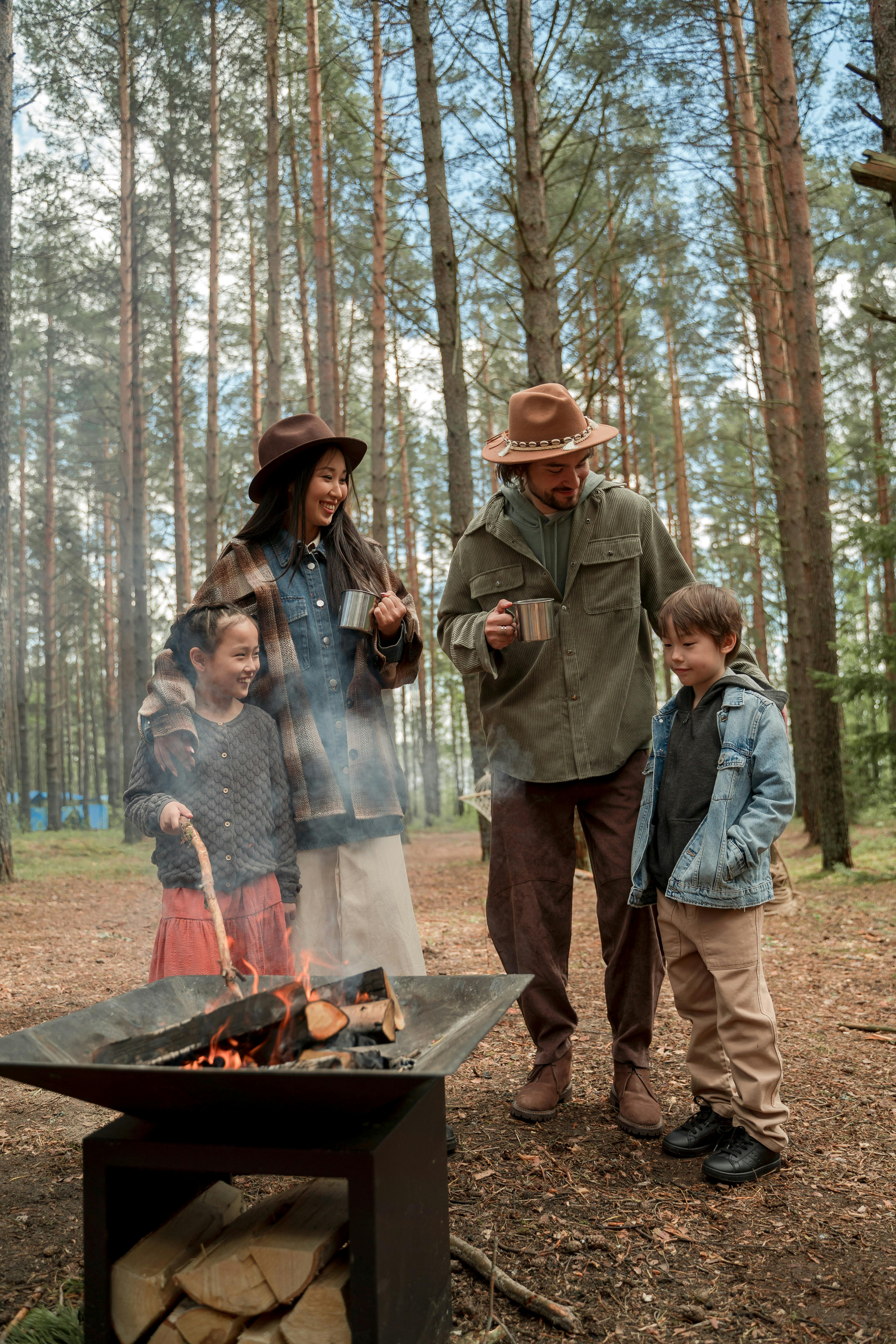 a happy family standing by a firepit in the woods
