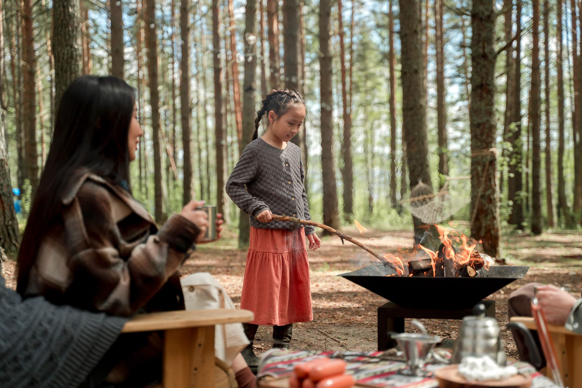 A Girl Holding a Stick while Standing by a Fire Pit