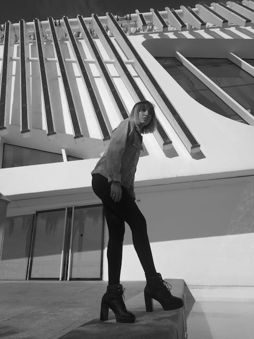 Grayscale Photo of a Woman Posing Outside a Building