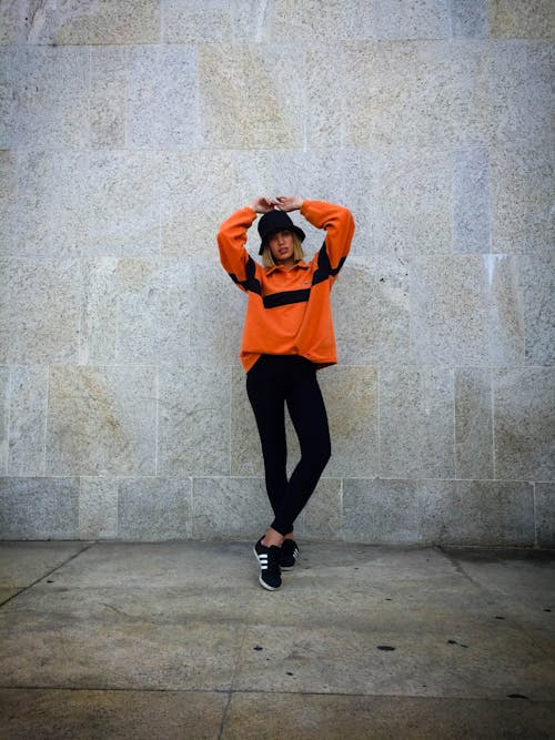 Woman in Orange Long Sleeves with Hands on Head