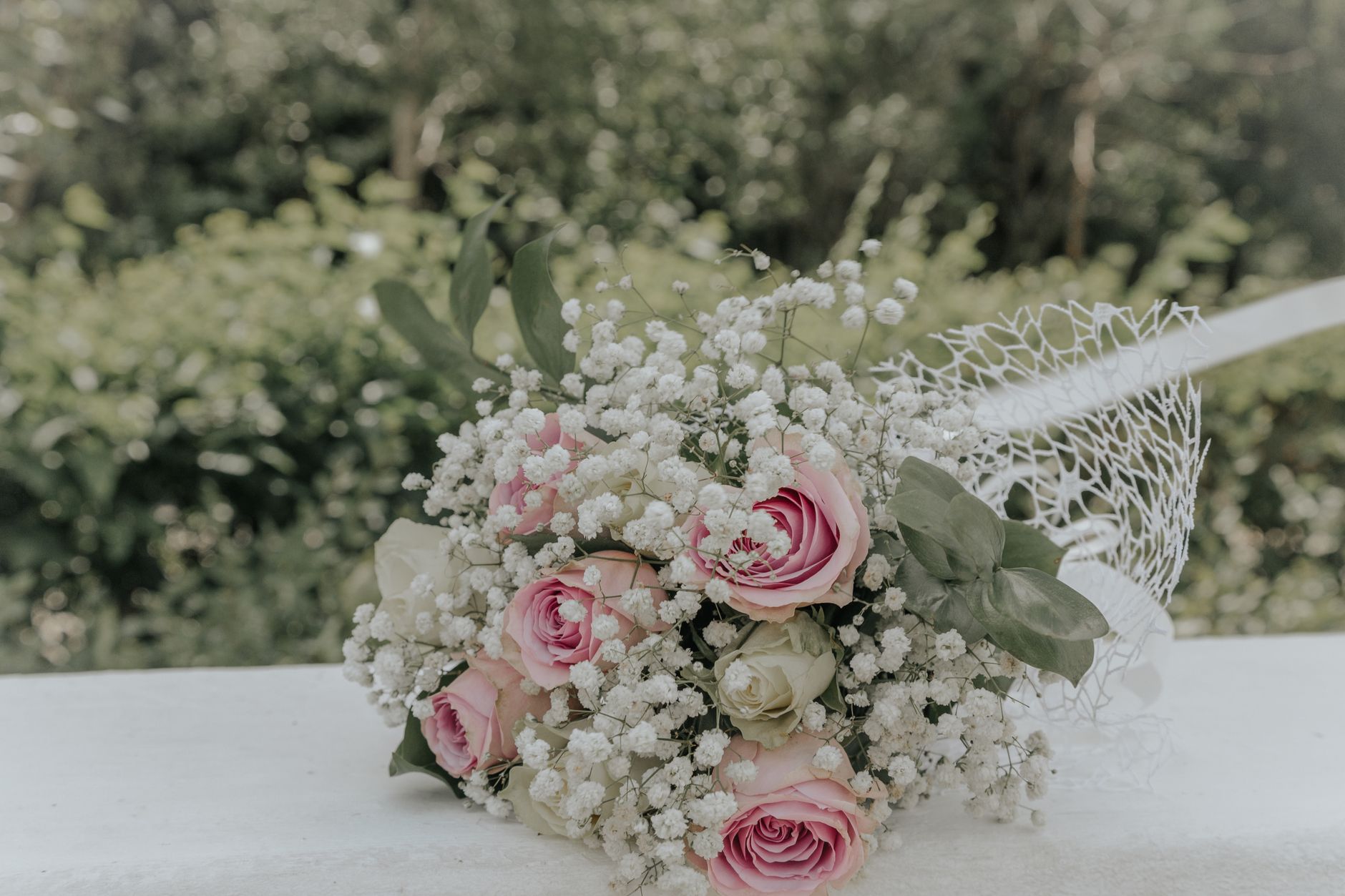 A beautiful bridal bouquet with pink roses and baby's breath, perfect for weddings.