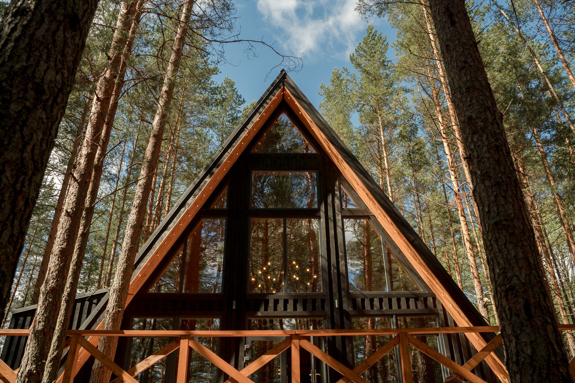 Modern glass A-frame house reflecting the forest