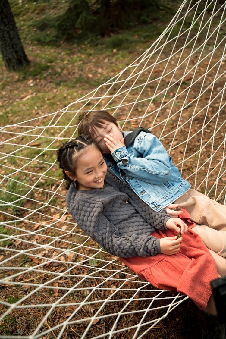 Cute Girl And Boy Sitting On Hammock